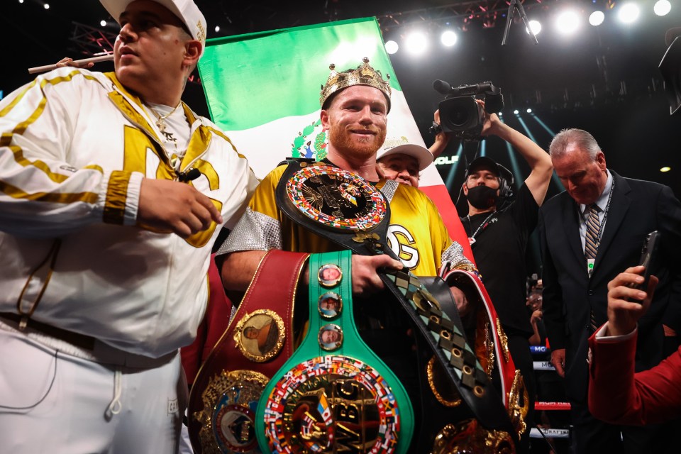 Canelo Alvarez holding boxing championship belts.