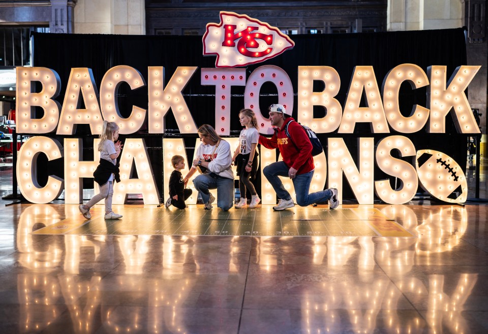 A family kneels in front of a sign celebrating the Super Bowl LVIII win of the Kansas City Chiefs at Union Station in Kansas City, on February 13, 2024. (Photo by ANDREW CABALLERO-REYNOLDS / AFP) (Photo by ANDREW CABALLERO-REYNOLDS/AFP via Getty Images)