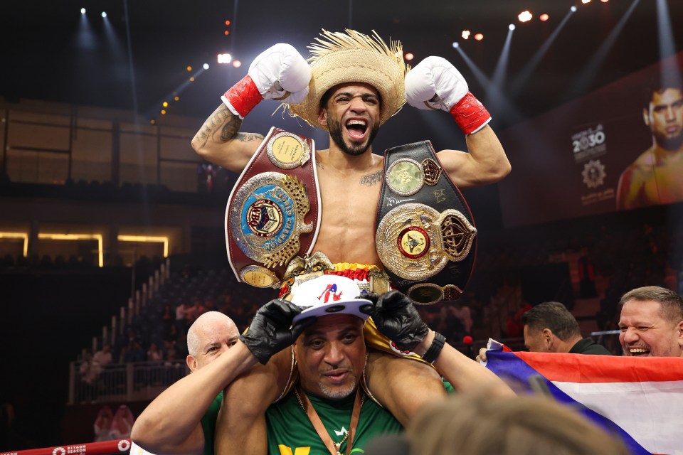 Oscar Collazo, unified WBA and WBO minimumweight world champion, celebrates with his belts.