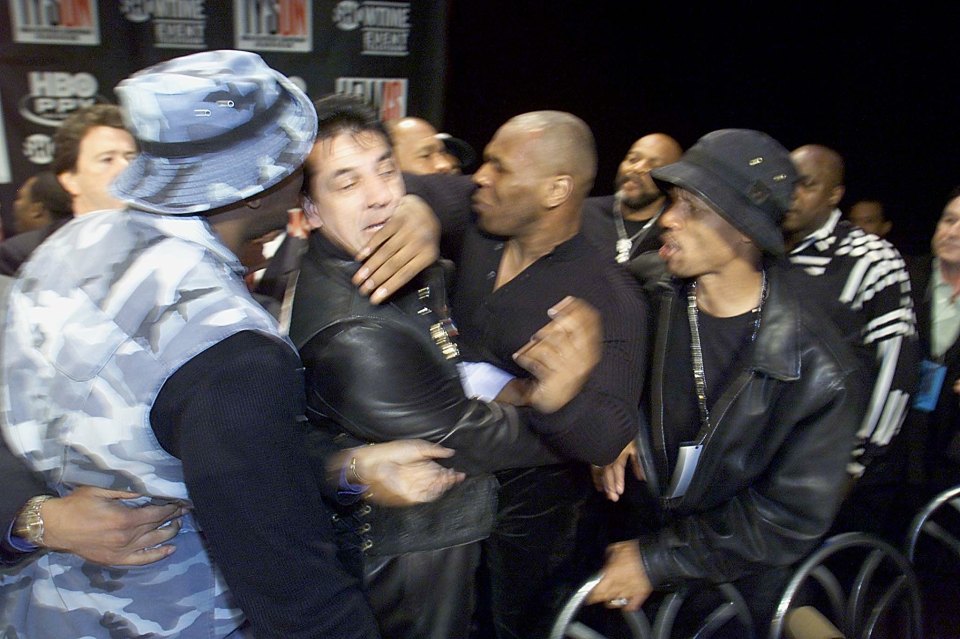 Heavyweight boxer Mike Tyson (C-R) is held back by promoters after a fight broke out at a news conference with Lennox Lewis 22 January, 2002  in New York. The fighters started to brawl and the news conference was cancelled.   AFP PHOTO   Don EMMERT (Photo by DON EMMERT / AFP) (Photo by DON EMMERT/AFP via Getty Images)