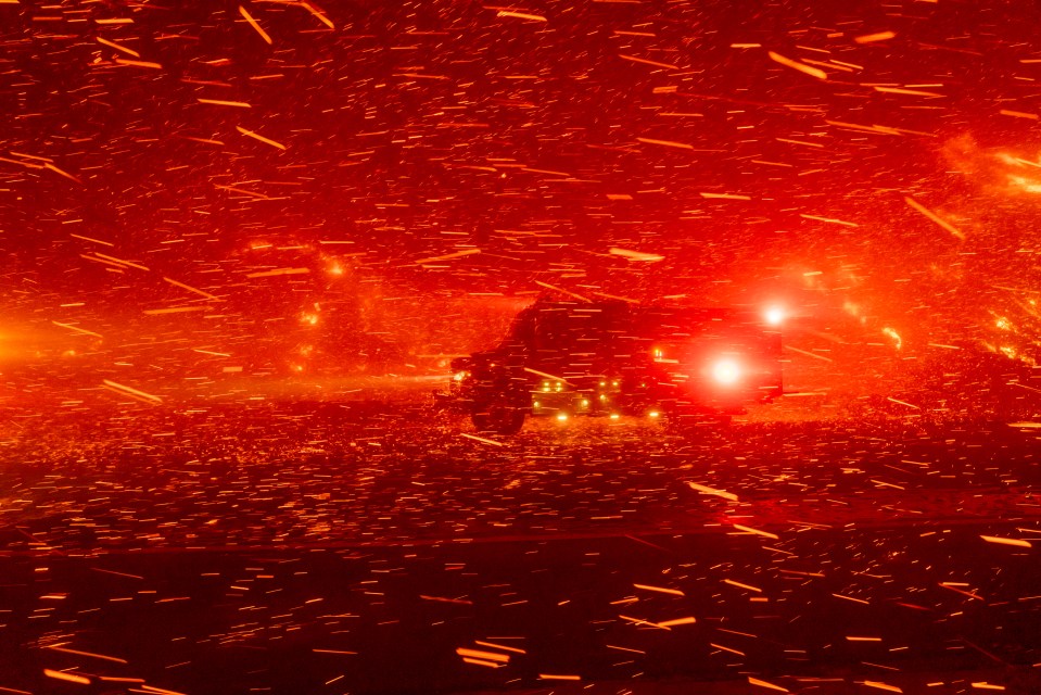 A fire truck drives through embers in LA