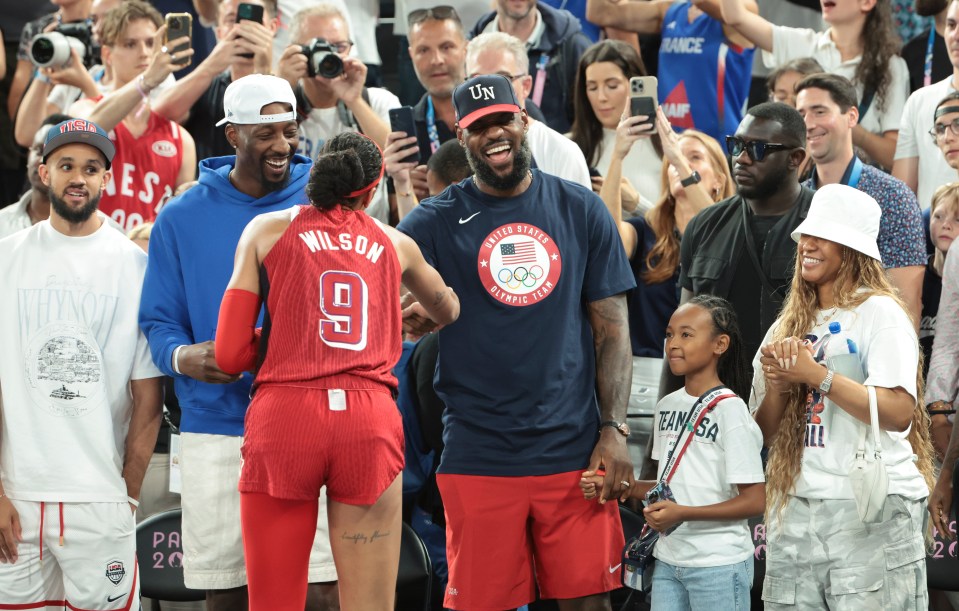 PARIS, FRANCE - AUGUST 11: Derrick White,  Bam Adebayo, LeBron James of USA, his daughter Zhuri James and his wife Savannah James congratulates A'ja Wilson of USA following the victory of Team USA following the Basketball Women's Gold Medal match between Team France and Team USA on day sixteen of the Olympic Games Paris 2024 at Bercy Arena on August 11, 2024 in Paris, France. (Photo by Jean Catuffe/Getty Images)