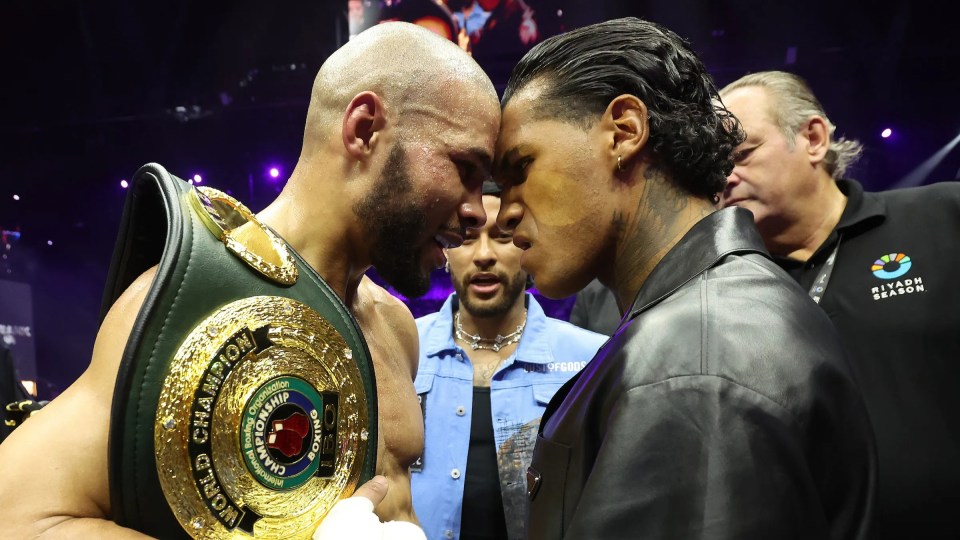 Two boxers facing each other, one holding a championship belt.
