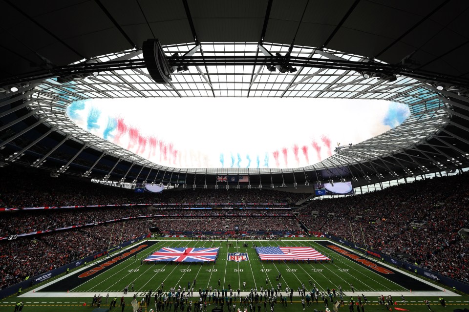 A packed stadium during a pre-game pyrotechnic display at an NFL game.  The UK and US flags are displayed on the field.