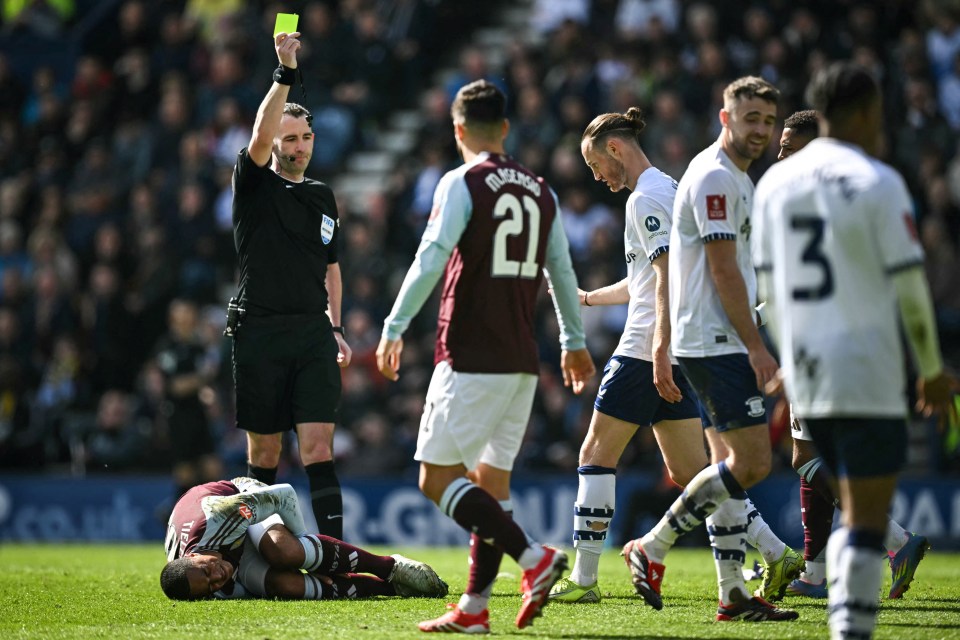 Referee Chris Kavanagh gives a yellow card to Preston's Irish striker #07 Will Keane (rear C) following a foul on Aston Villa's Belgian midfielder #08 Youri Tielemans (down L) during the English FA Cup quarter-final football match between Preston North End and Aston Villa at Deepdale stadium in Preston, north-west England on March 30, 2025. (Photo by Paul ELLIS / AFP) / RESTRICTED TO EDITORIAL USE. No use with unauthorized audio, video, data, fixture lists, club/league logos or 'live' services. Online in-match use limited to 120 images. An additional 40 images may be used in extra time. No video emulation. Social media in-match use limited to 120 images. An additional 40 images may be used in extra time. No use in betting publications, games or single club/league/player publications. /  (Photo by PAUL ELLIS/AFP via Getty Images)